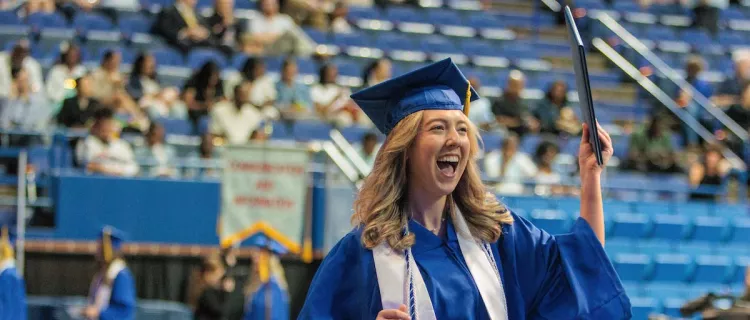 A grad holds up a diploma at the UK Martin-Gatton CAFE 2024 spring commencement ceremony at Rupp Arena.