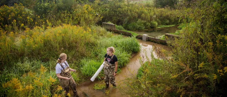 Biosystems and Agricultural Engineering students Katherine Ristola and Emma Sharek collect water samples from a spring at the C. Oran Little Research Farm outside Versailles, Ky.