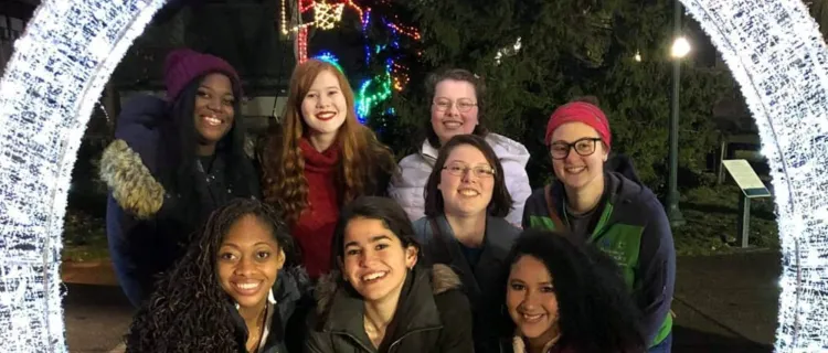 Collegiate 4-H members stand with holiday lights