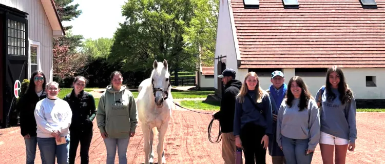 Horse Racing Club members stand with a horse on a trip