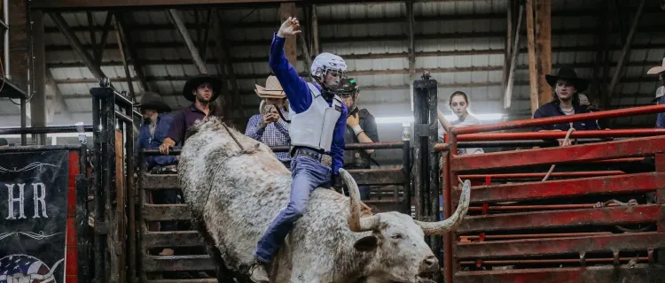 A Rodeo Team member rides a bull