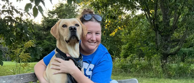 A Wildcat Service Dogs member sits with a dog