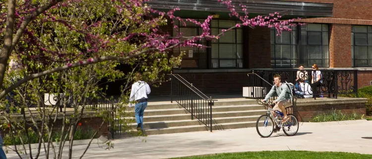 Students ride bikes in front of Erikson Hall