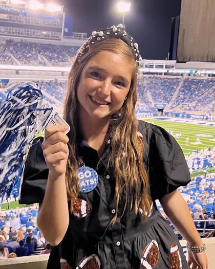 Kayleigh Thomas holds a pompom at a football game