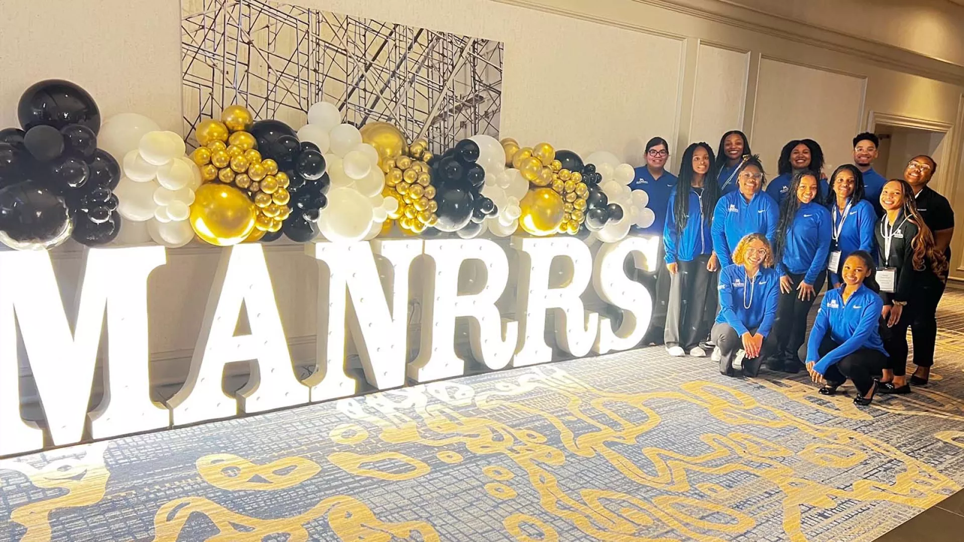 A group of people stand beside a MANRRS sign at an event