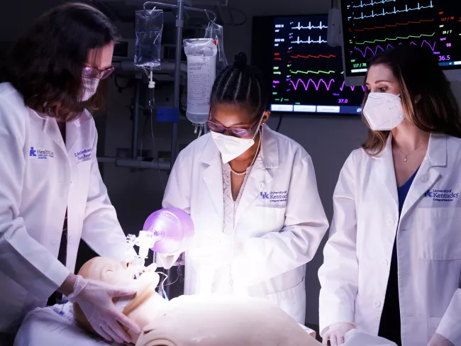 Three students work on a practice patient in the College of Medicine.