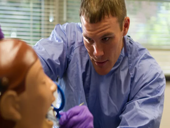 A dental student works with a practice patient