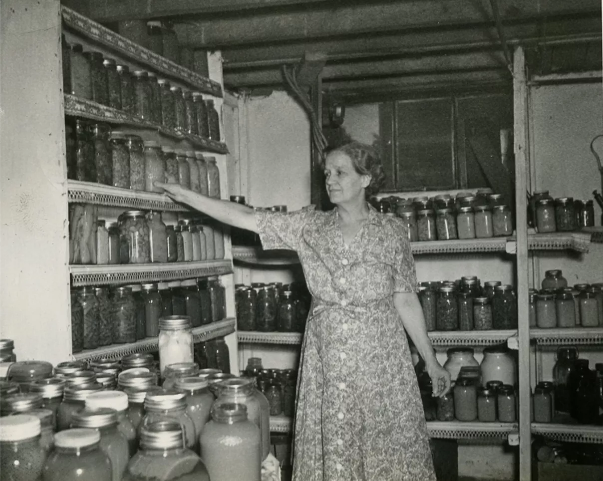 A woman with preserved food in a cellar