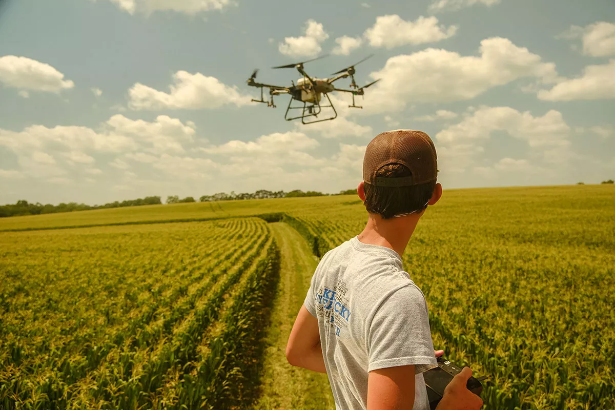 Student flying a drone in a field