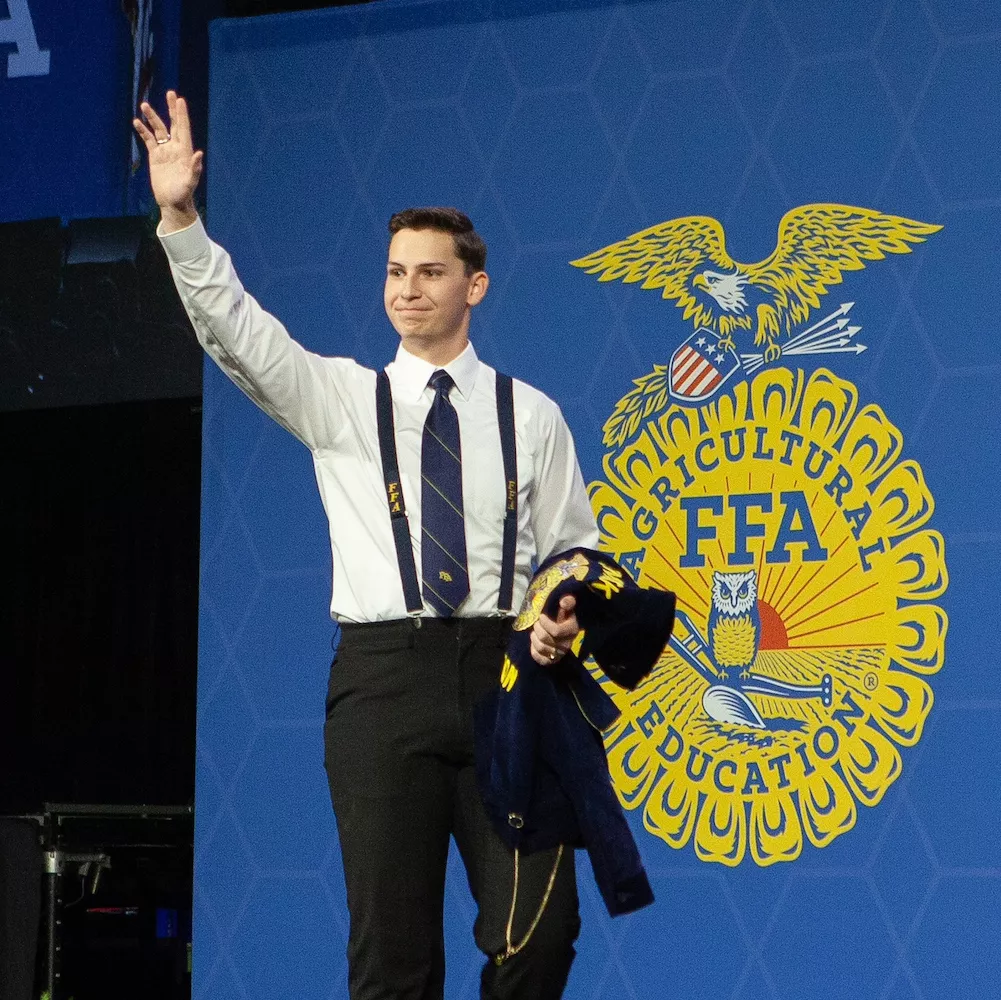 Ben Williams waves in front of an FFA logo backdrop