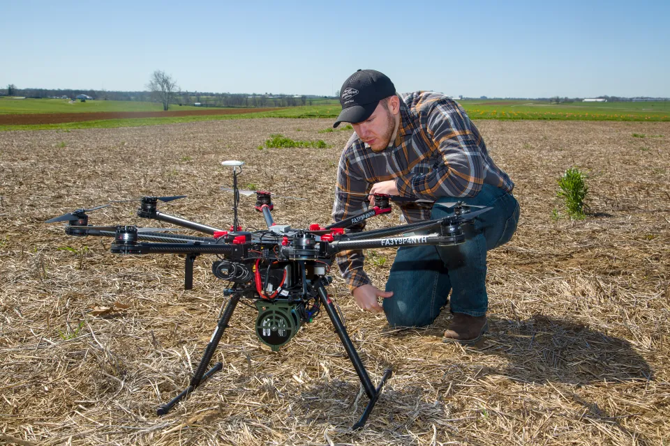 Student checking on drone setup in field