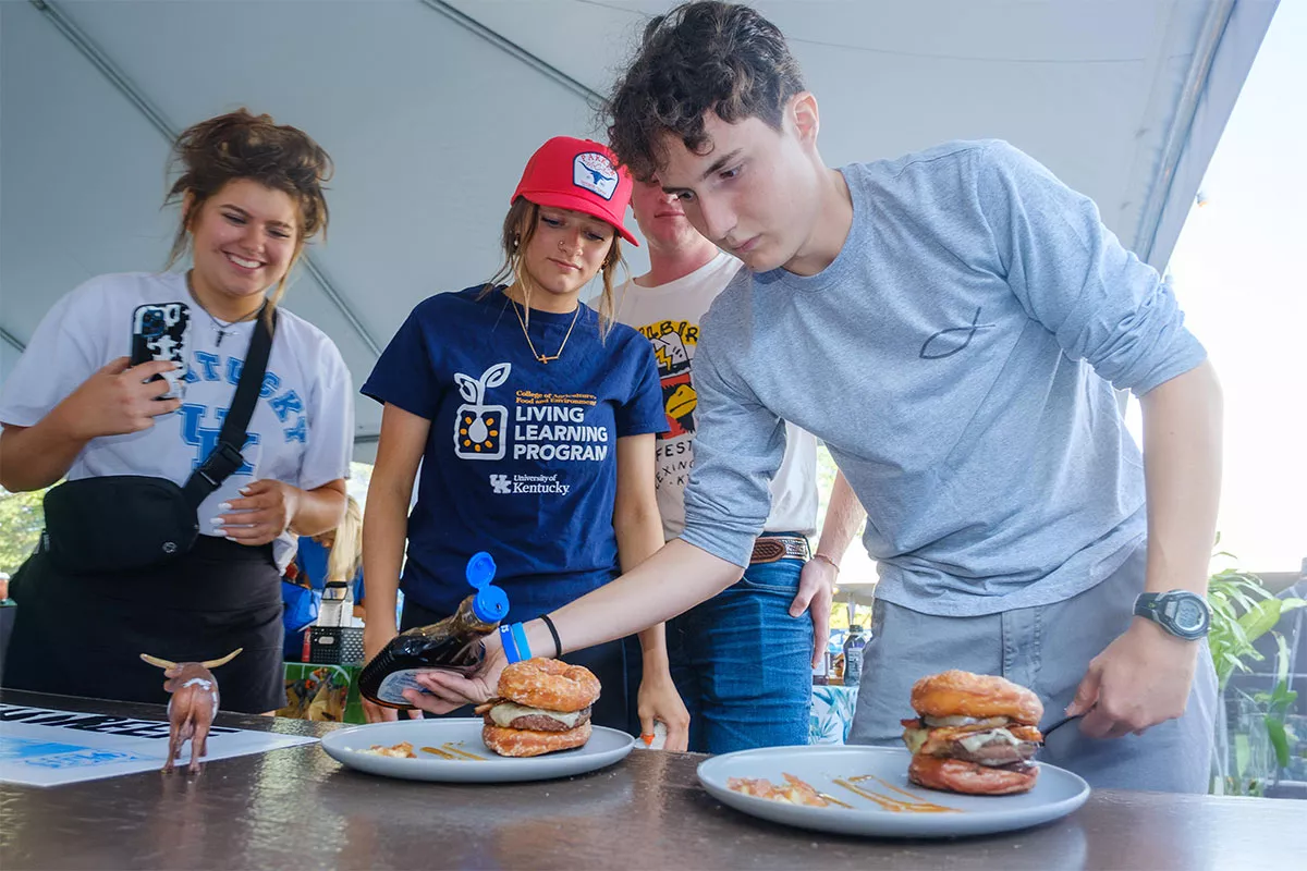 Student adding syrup to donut burger during annual burger contest